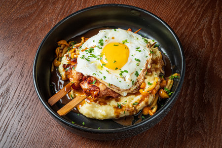 Savory grilled meat topped with a sunny-side-up egg on a bed of rich mashed potatoes and mushrooms.の写真素材