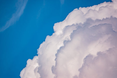Billowing clouds take center stage in a bright blue sky, creating a serene summer scene.