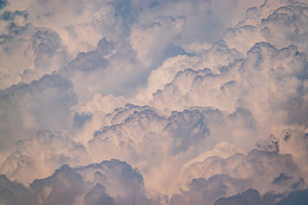 Puffy clouds take on soft tones of pink and blue, creating a peaceful sky at dusk.