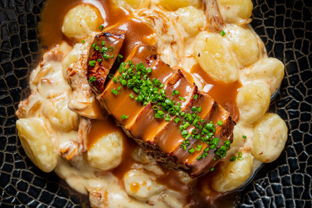 Tender roasted meat rests atop a bed of creamy gnocchi, enriched with savory sauce and herbs.の写真素材