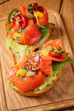 Freshly made avocado toast features smoked salmon, tomatoes, and greens, perfect for brunch.の写真素材