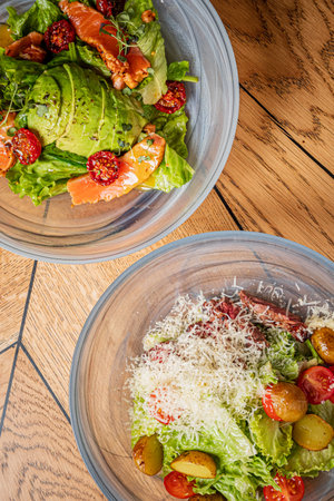 Colorful salad bowls feature fresh greens, cherry tomatoes, and cheese for a light meal.の写真素材