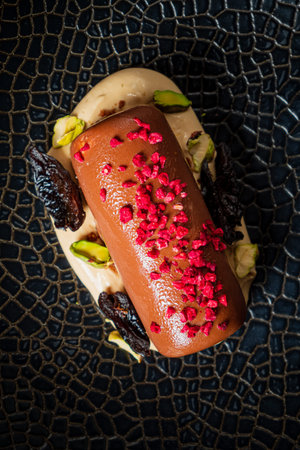 Luxurious dessert showcases chocolate cake topped with nuts and colorful raspberry sprinkles.