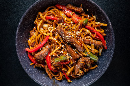Savory stir-fried noodles with tender beef and vibrant peppers served in a stylish bowl.