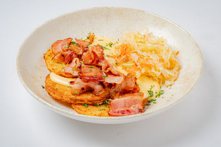 Golden potato pancakes topped with crispy bacon and sauerkraut make a hearty breakfast delight.の写真素材