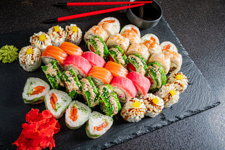 Enjoy a vibrant array of fresh sushi rolls artfully displayed on dark stone.の写真素材