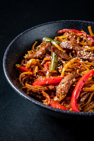 A vibrant dish of stir-fried beef, bell peppers, and sesame seeds arranged beautifully.の写真素材