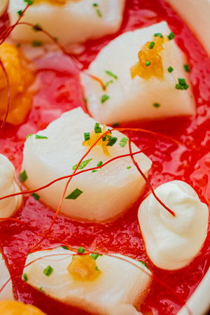Fresh scallops with a rich red sauce and elegant garnishes showcase culinary art.の写真素材