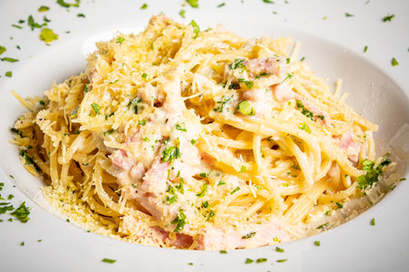 Savor rich spaghetti carbonara topped with herbs and cheese for a comforting meal.の写真素材