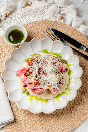 Savor a beautifully arranged plate of tender meat, herbs, and cheese, highlighting culinary art.の写真素材