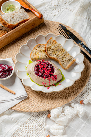 A creamy dish adorned with berry jam sits alongside toasted bread on a rustic table.の写真素材