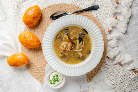 Delicious soup is served in a white bowl alongside golden bread rolls, creating a cozy meal setting.の写真素材