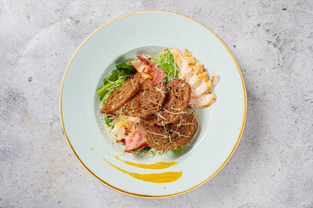 A vibrant salad features mixed greens, chicken slices, crispy croutons, and a touch of dressing.の写真素材