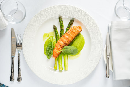 Salmon steak with fresh asparagus and spinach purÃ©e on a white tablecloth.の写真素材