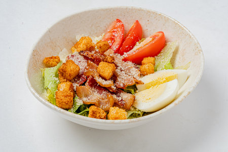 A vibrant salad with fresh lettuce, tomatoes, croutons, bacon, and cheese.の写真素材
