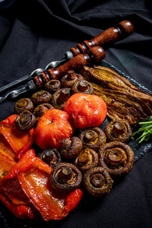 Colorful grilled mushrooms and veggies on a slate board create a warm atmosphere.の写真素材