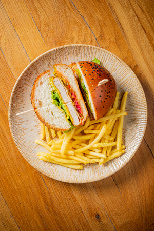 A tasty burger filled with fresh ingredients and crispy fries sits invitingly on a rustic plate.の写真素材