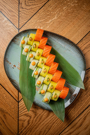 Artfully arranged sushi with salmon and assorted vegetables sits elegantly on a stylish plate.の写真素材