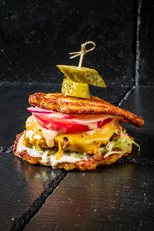 A delicious burger made with fried plantains, topped with cheese, pickles, and fresh vegetables.の写真素材