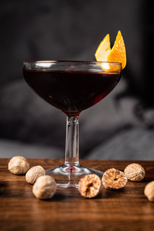 Sipping on a dark cocktail adorned with nutmeg and orange enhances the cozy atmosphere.の写真素材