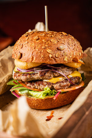 A tempting burger showcases juicy patties, cheese, and fresh vegetables in a hearty bun.の写真素材