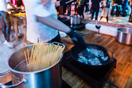 A chef skillfully prepares pasta and seafood at a festive gathering, surrounded by excited guests.の写真素材