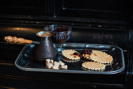 Traditional coffee with crispy wafers and cherry preserves on an elegant tray.の写真素材