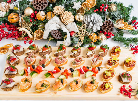 Colorful appetizers delightfully arranged on a table, surrounded by joyful Christmas decorations.の写真素材