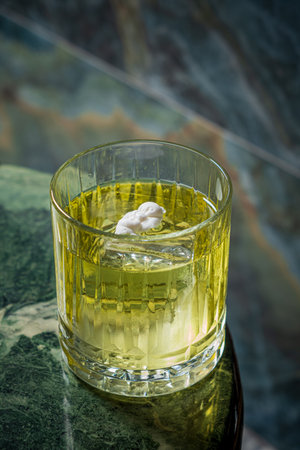 A vibrant cocktail in a crystal glass rests on a marble surface, inviting enjoyment.の写真素材