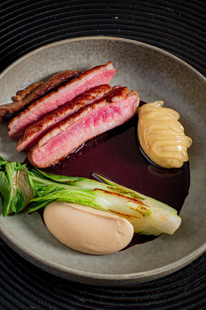 Tender duck breast paired with savory sides on a stylish plate highlights culinary artistry.の写真素材