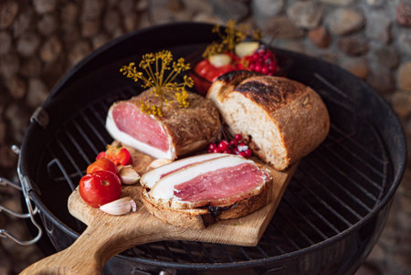Smoked meat surrounded by fresh vegetables, ready for a summer cookout in a garden.の写真素材