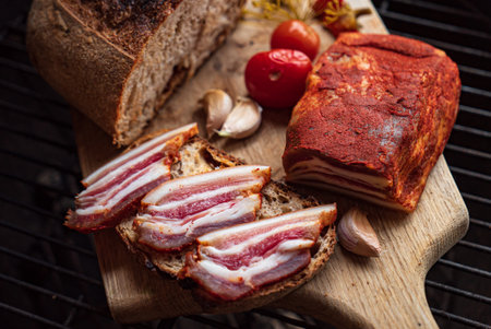 Freshly sliced bread topped with smoked bacon and juicy tomatoes creates a perfect treat outside.の写真素材