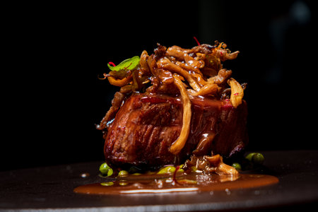 Succulent steak with mushrooms and herbs, served on a glossy sauce for an exquisite flavor.の写真素材