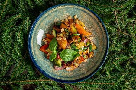Freshly prepared vegetable stir-fry bursting with colors, topped with nuts, on a decorative plate.の写真素材
