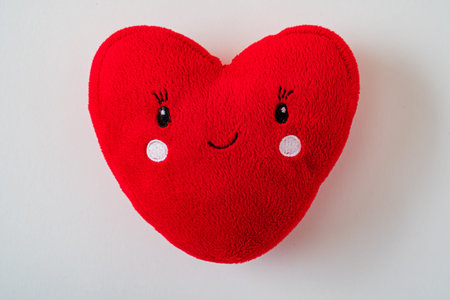 A cheerful red heart-shaped toy rests on a neutral background, spreading joy.の写真素材
