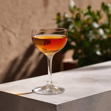 Enjoy a beautifully crafted Froupe cocktail, glimmering in the sunlight, on a stylish surface.の素材