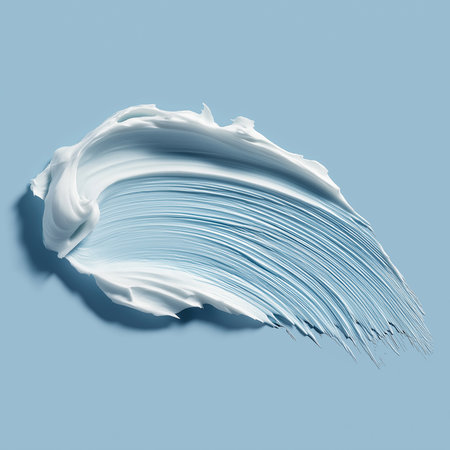 Soft cream gently spreads against a calming blue background, showcasing smooth textures and tones.の素材