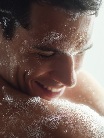 A young man smiles happily while enjoying a bubble bath, feeling relaxed and carefree.の素材