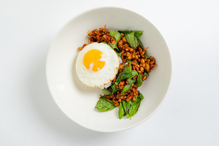A colorful bowl features savory ground chicken mixed with spinach, topped with a sunny side up egg.の写真素材