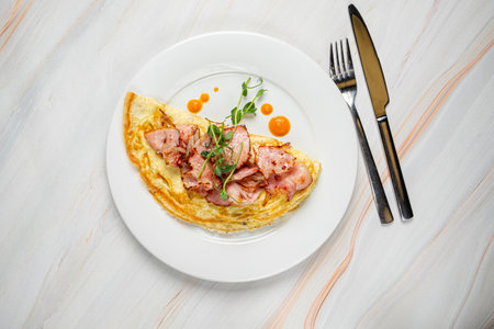 Enjoy a delicious ham and cheese omelet presented on a white plate with garnish.の写真素材