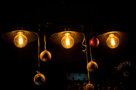 Soft yellow glow shines from hanging bulbs while shiny ornaments dangle, creating a festive feel.