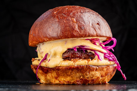 A freshly made burger features a juicy patty, creamy sauce, and vibrant red slaw in a soft bun.の写真素材