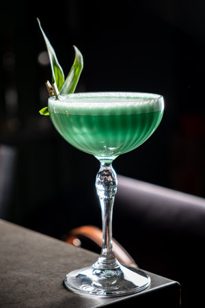 A vibrant green cocktail sits elegantly in a glass, showcasing its refreshing appeal at the bar.の写真素材