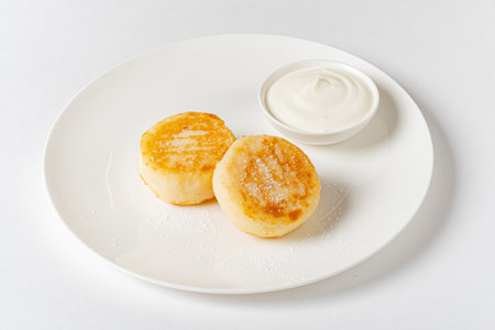 Fluffy pancakes on a white plate, perfectly golden and served with a smooth dipping sauce.の写真素材