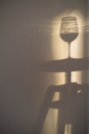 A wine glass silhouette casts a gentle shadow, capturing the golden hour light.の写真素材