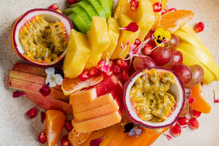 A colorful mix of grapes, pineapples, and passion fruit, beautifully garnished with flowers.の写真素材