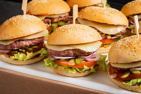 A lively setting showcases freshly made burgers stacked high with colorful toppings, ready to enjoy.の写真素材