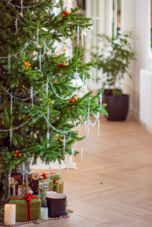 A cozy indoor scene featuring a festive Christmas tree adorned with sparkling decorations and gifts.の写真素材