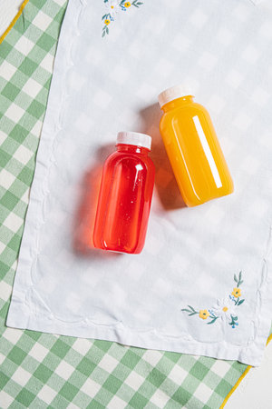 Bright red and yellow glass bottles sit atop a green and white checkered cloth, adding cheer.の写真素材