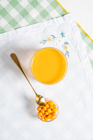 A refreshing orange drink sits beside a small bowl of cheerful yellow berries, inviting taste.の写真素材